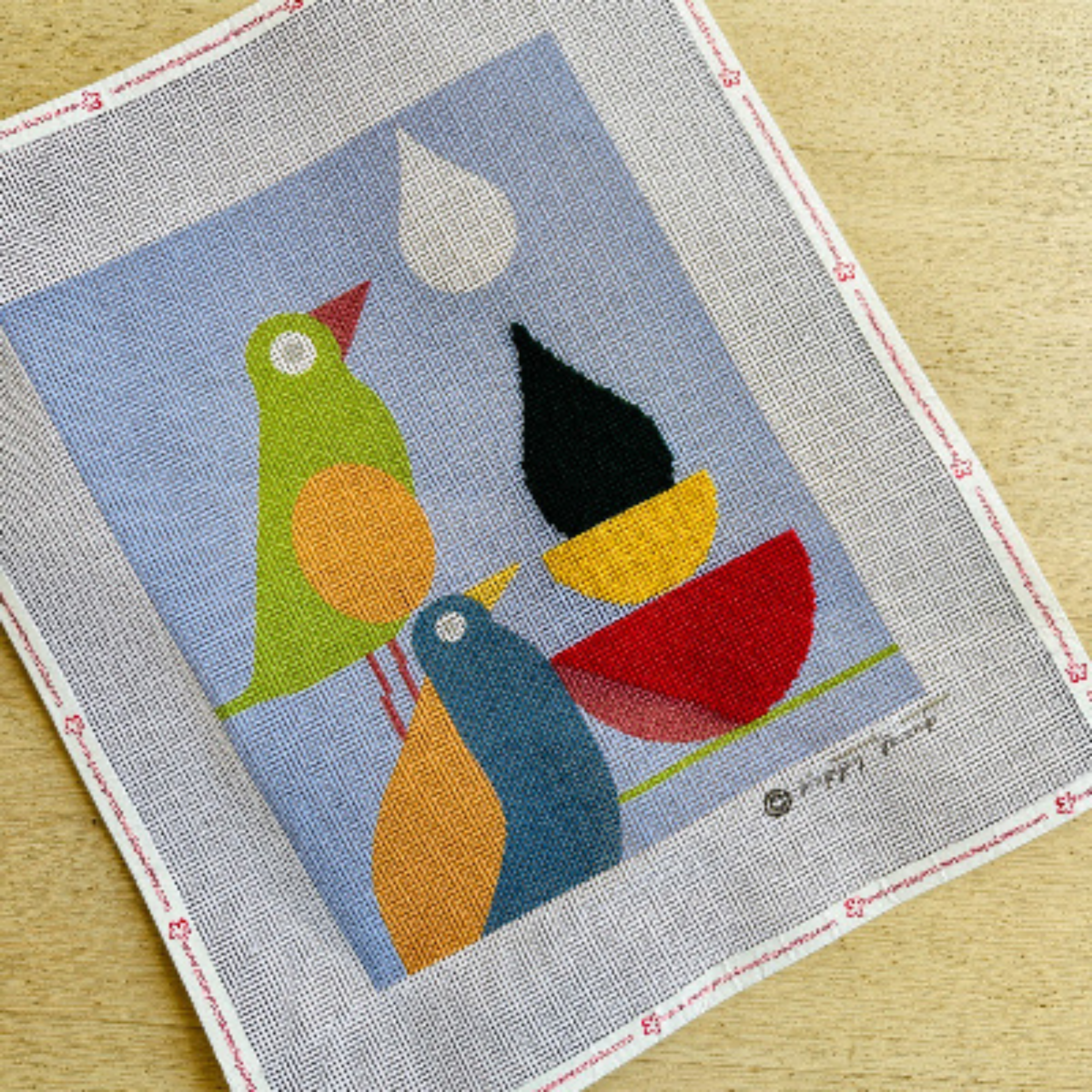 Textile art piece with colorful birds on a blue background