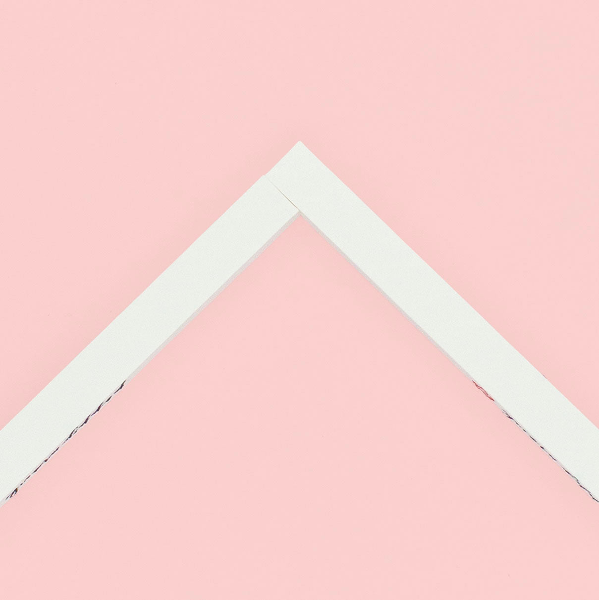 Two stretcher bars joined together making a corner lying on a pink background.