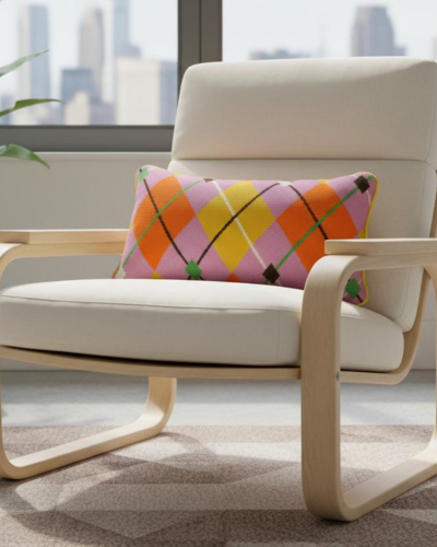Beige chair with a colorful argyle pillow in a room with large windows.