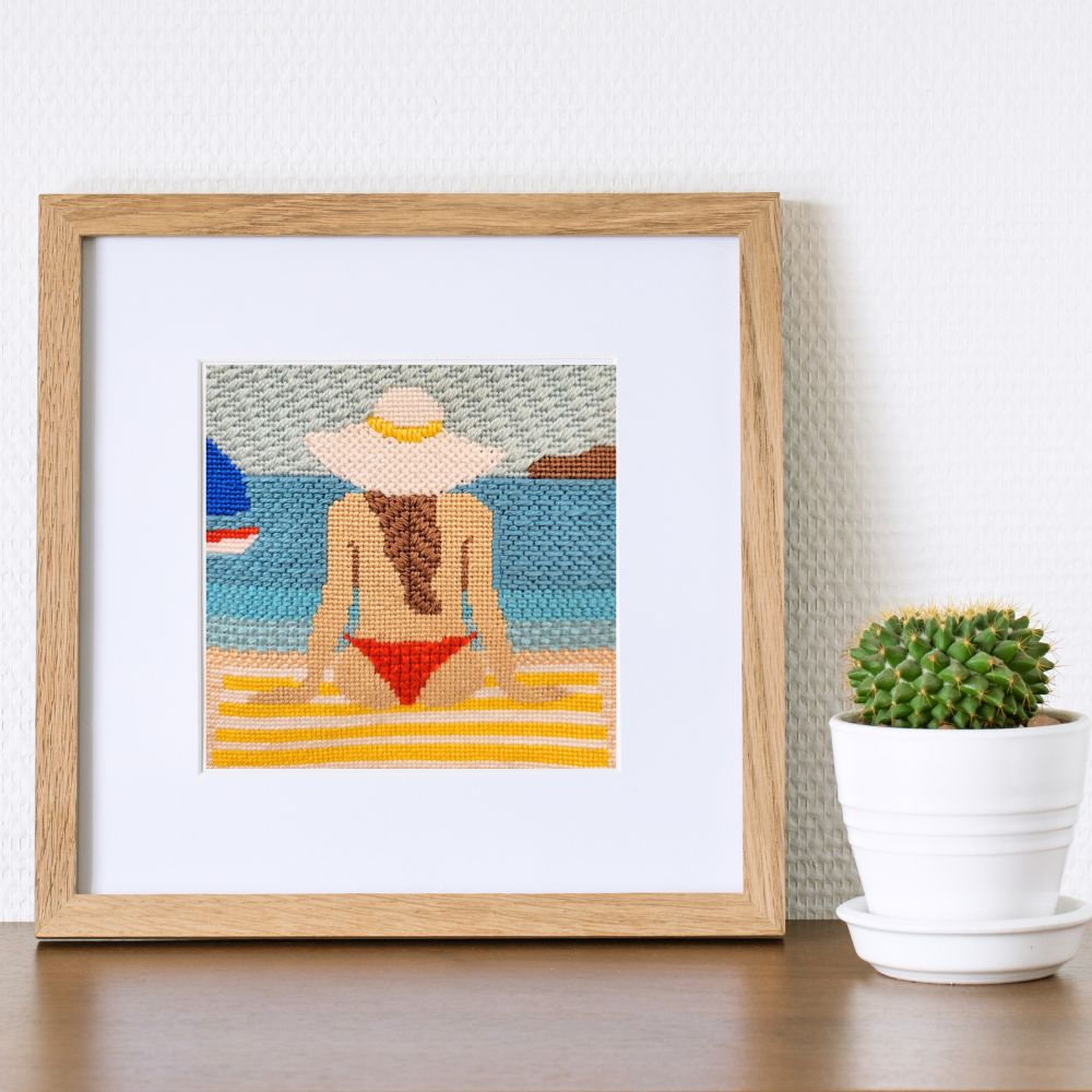 framed needlepoint picture of a woman in a bikini