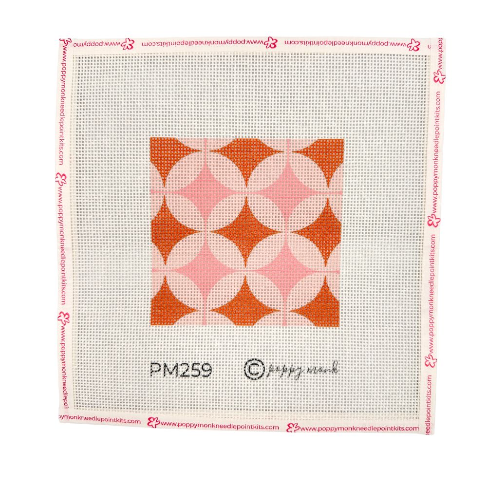 A geometric needlepoint design in orange and pinks shown in a white frame