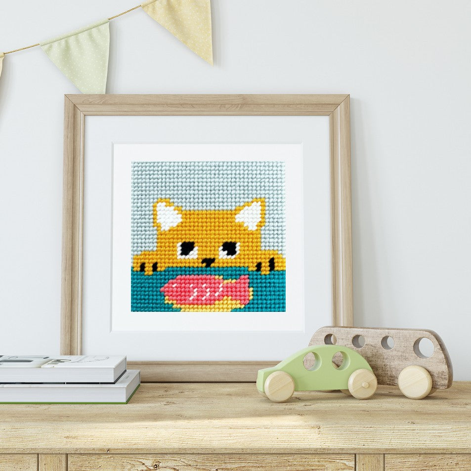 Framed needlepoint of a cat, on a shelf with toys