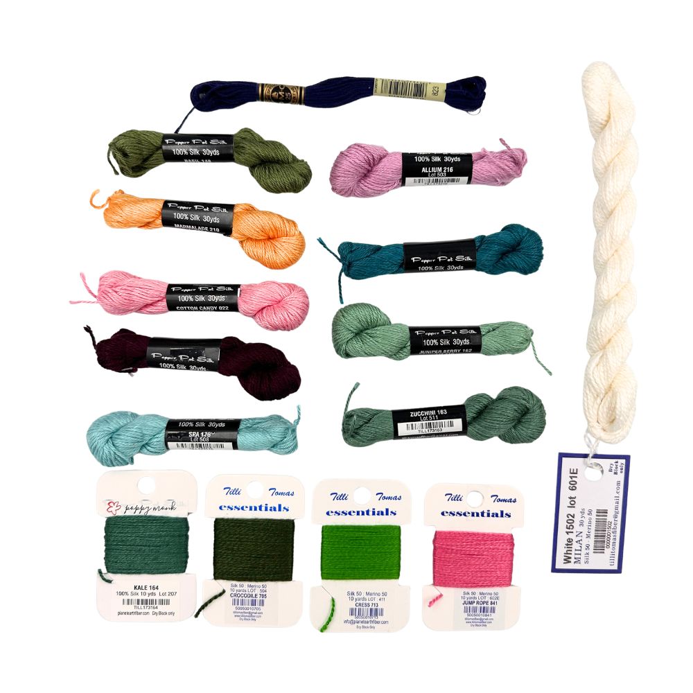 A collection of colorful needlepoint thread skeins and a larger cream-colored spool, displayed on a clean white background.