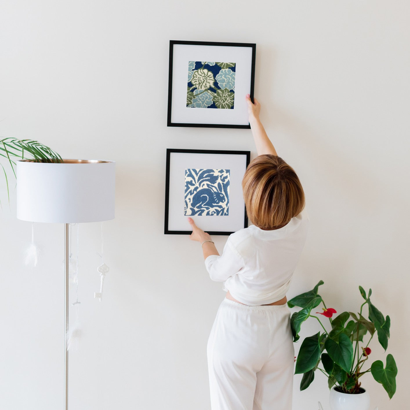 woman hanging two needlepoint designs