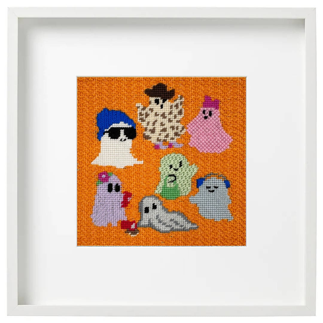 A framed needlepoint design of ghsots at a party