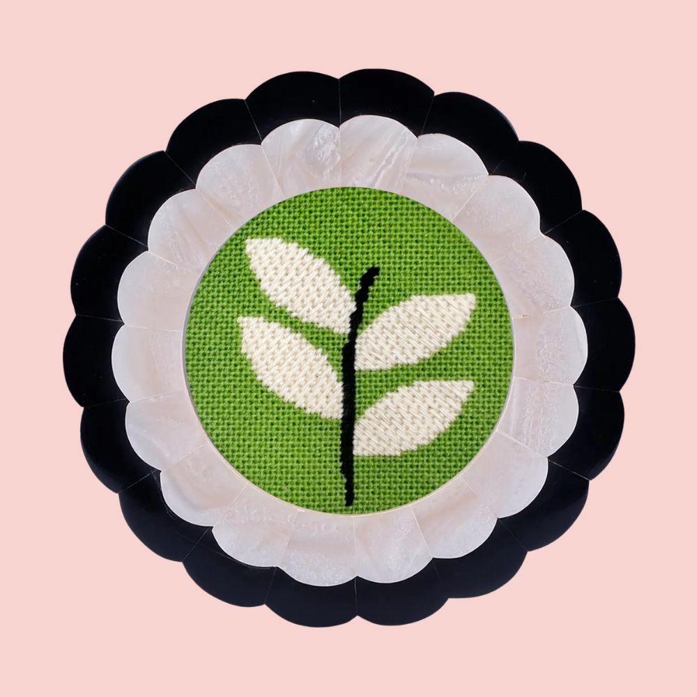 Modern leaf needlepoint design with decorative stitches shown in a navy scalloped frame