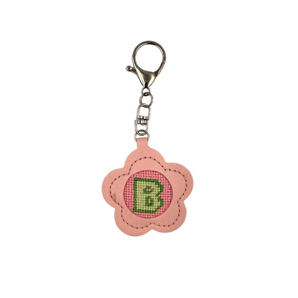 Pink flower-shaped keychain with a green letter &