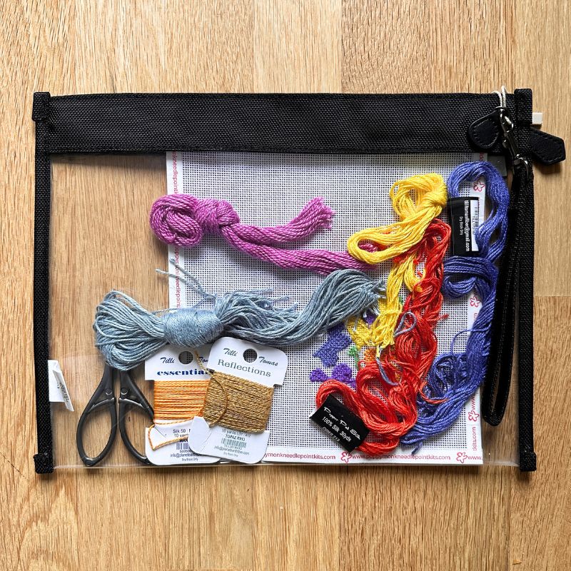 Embroidery thread set with scissors and tools in a clear pouch on a wooden surface