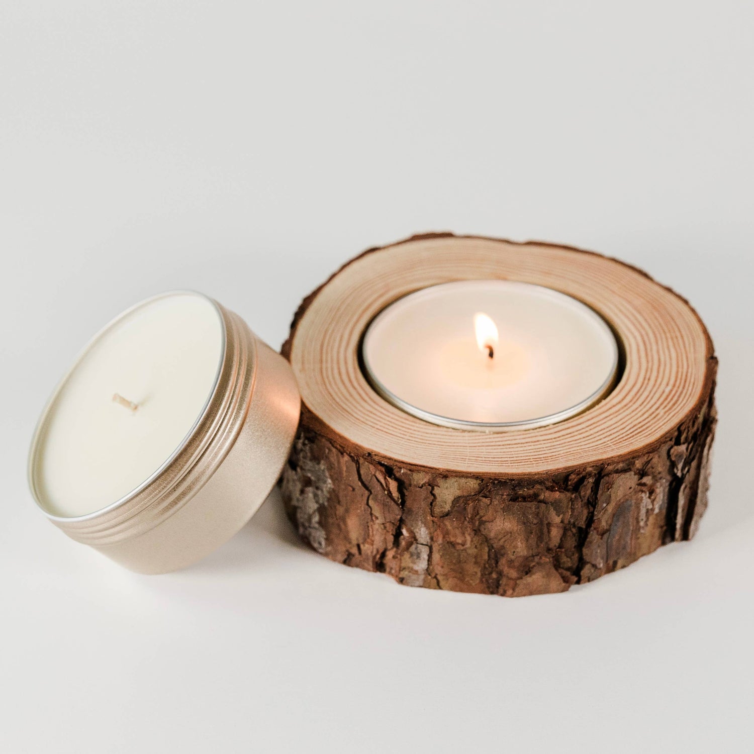 Candle inside a wooden log on a light gray background