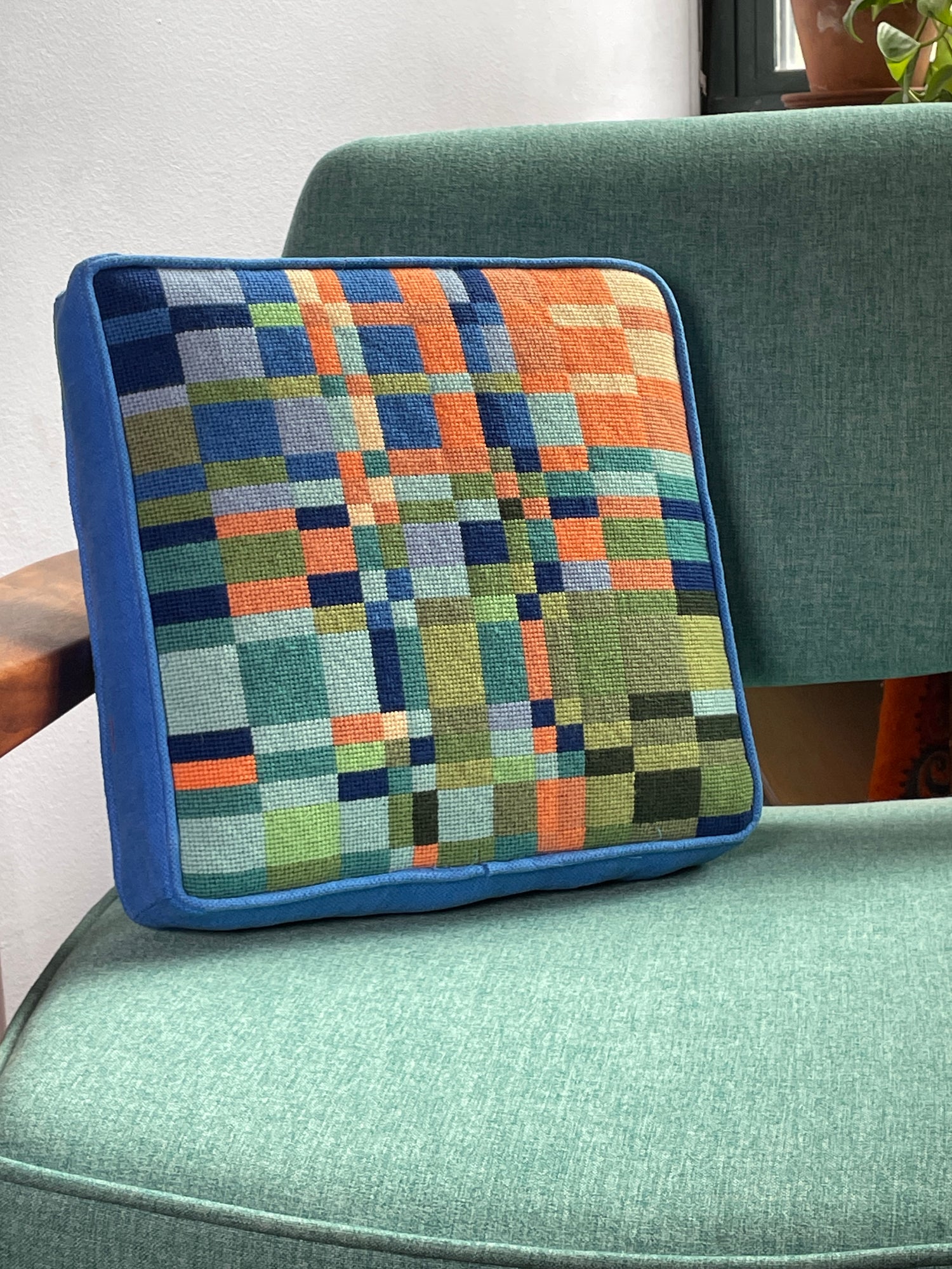 Colorful needlepoint pillow kit on a chair