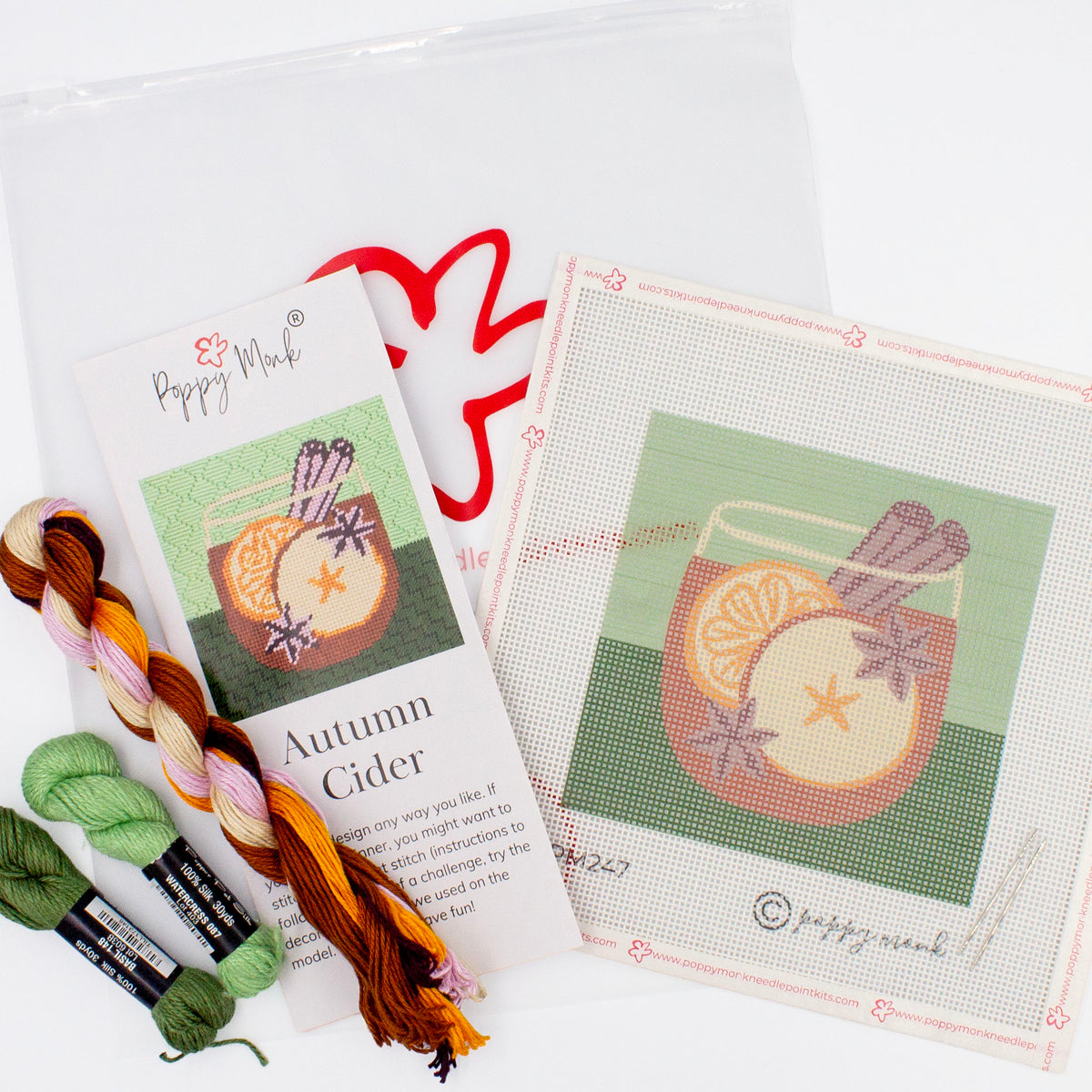 The Autumn Cider Kit components on a white backdrop. This includes the canvas with the printed design, colorful threads, instructional brochure, and a bag with the Poppy Monk logo on it.