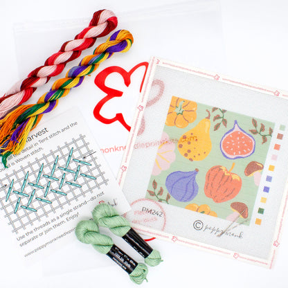 The Fall Harvest kit components on a white background. This includes the printed canvas, colorful threads, an instruction card, needles, and a plastic carrying bag with the Poppy Monk logo on it.
