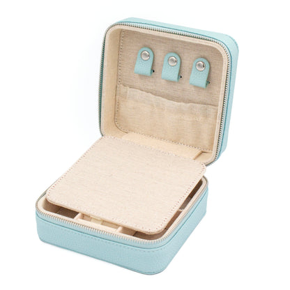 An open light blue jewelry organizer case with a beige fabric interior, showing three small turquoise ear clips and storage compartments.