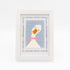 The Lucy Goosey kit stitched and in a white frame with a mat with a decorative blue watercolor bamboo border.