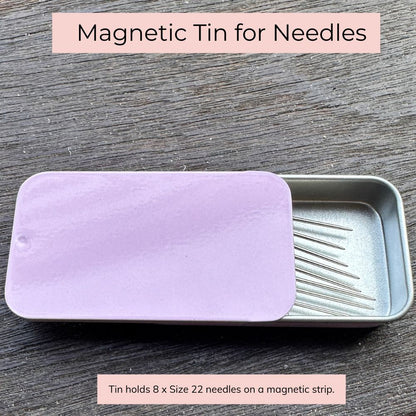 Magnetic tin for needles with a purple lid on a wooden surface