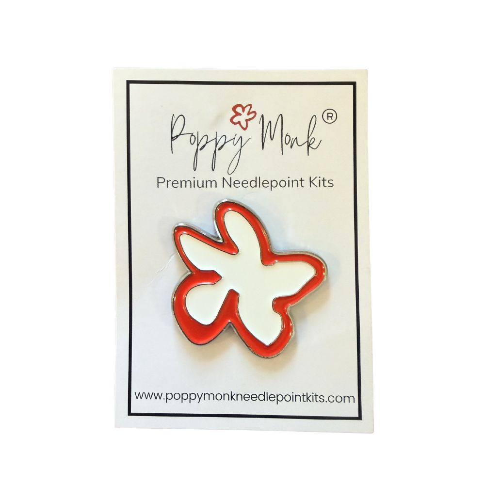 A poppy shaped needle minder shown on a card