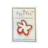 A poppy shaped needle minder shown on a card