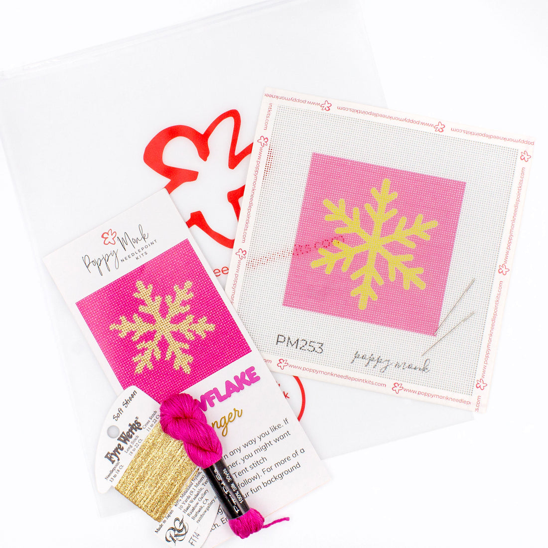 The Snowflake kit components on a white background. There is a canvas with the design, an instructional brochure, colorful threads, needles, and clear bag with the Poppy Monk logo on it.
