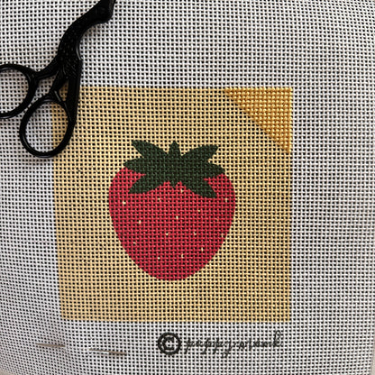 Needlepoint strawberry design partially stitched.