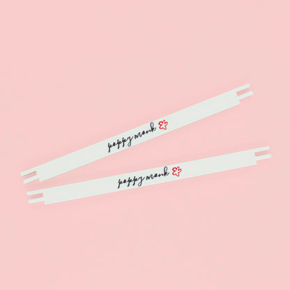 Two white stretcher bars with the Poppy Monk logo printed on them lying on a pink background.