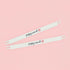 Two white stretcher bars with the Poppy Monk logo printed on them lying on a pink background.