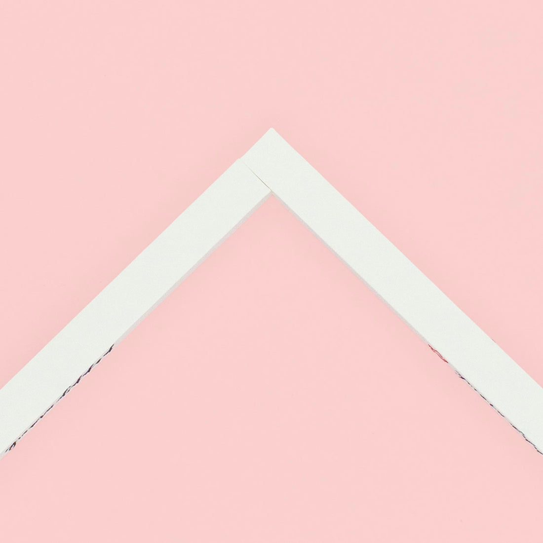 Two stretcher bars joined together making a corner lying on a pink background.