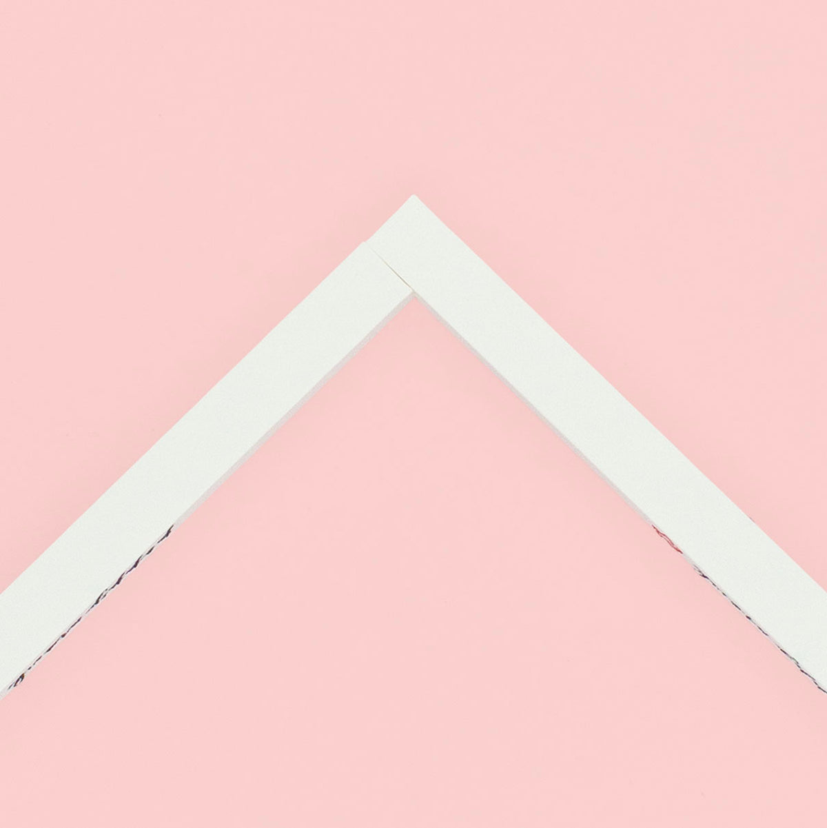 Two stretcher bars joined together making a corner lying on a pink background.