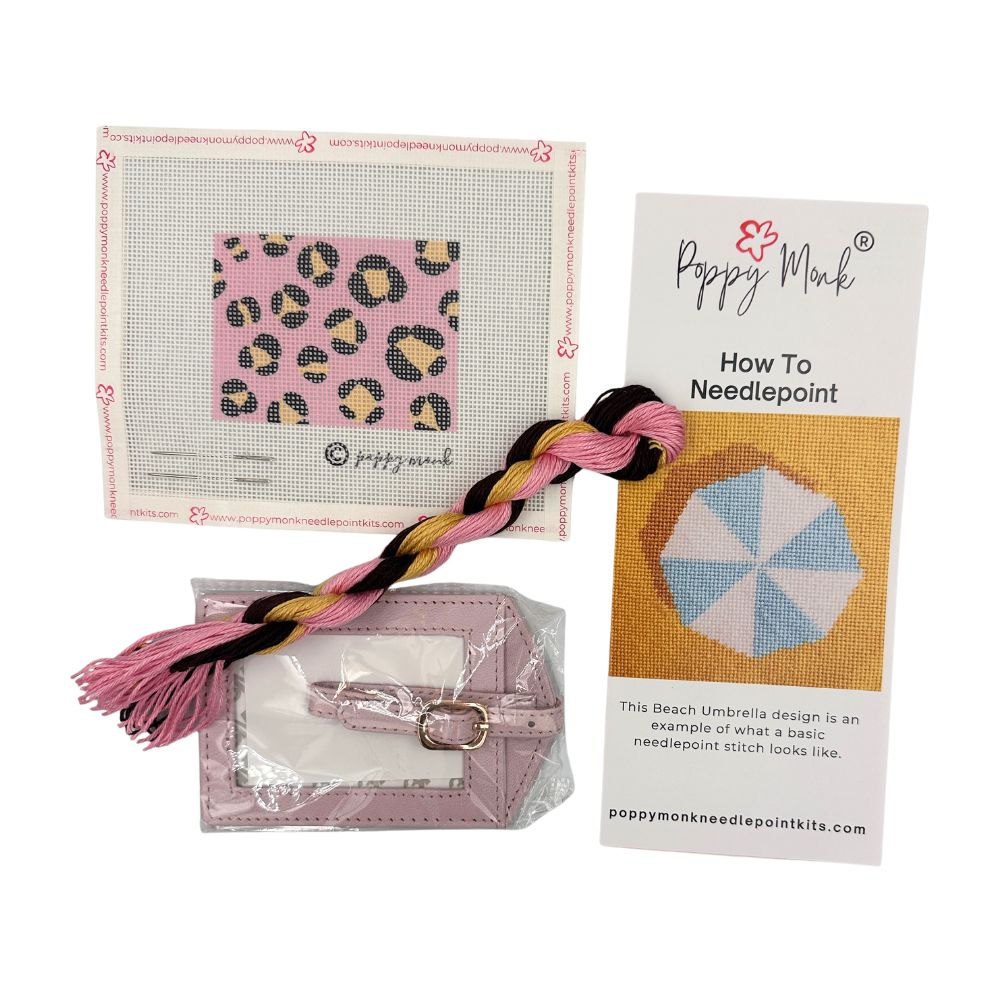 Needlepoint kit with patterned fabric, needle, thread, and Poppy Monk instruction manual on a white background