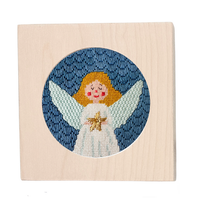 Needlepoint angel design on a wooden block with a blue circular background