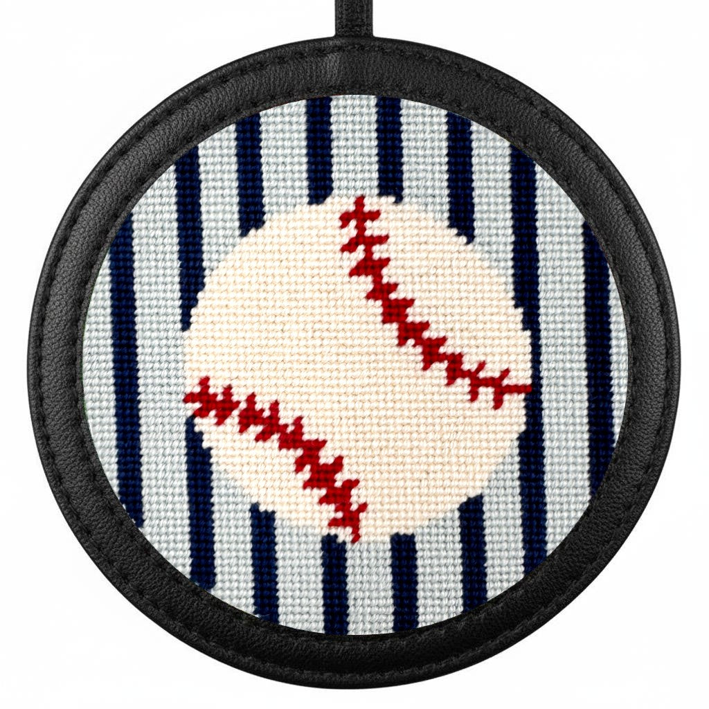 Circular needlepoint baseball ornament in a black leather holder