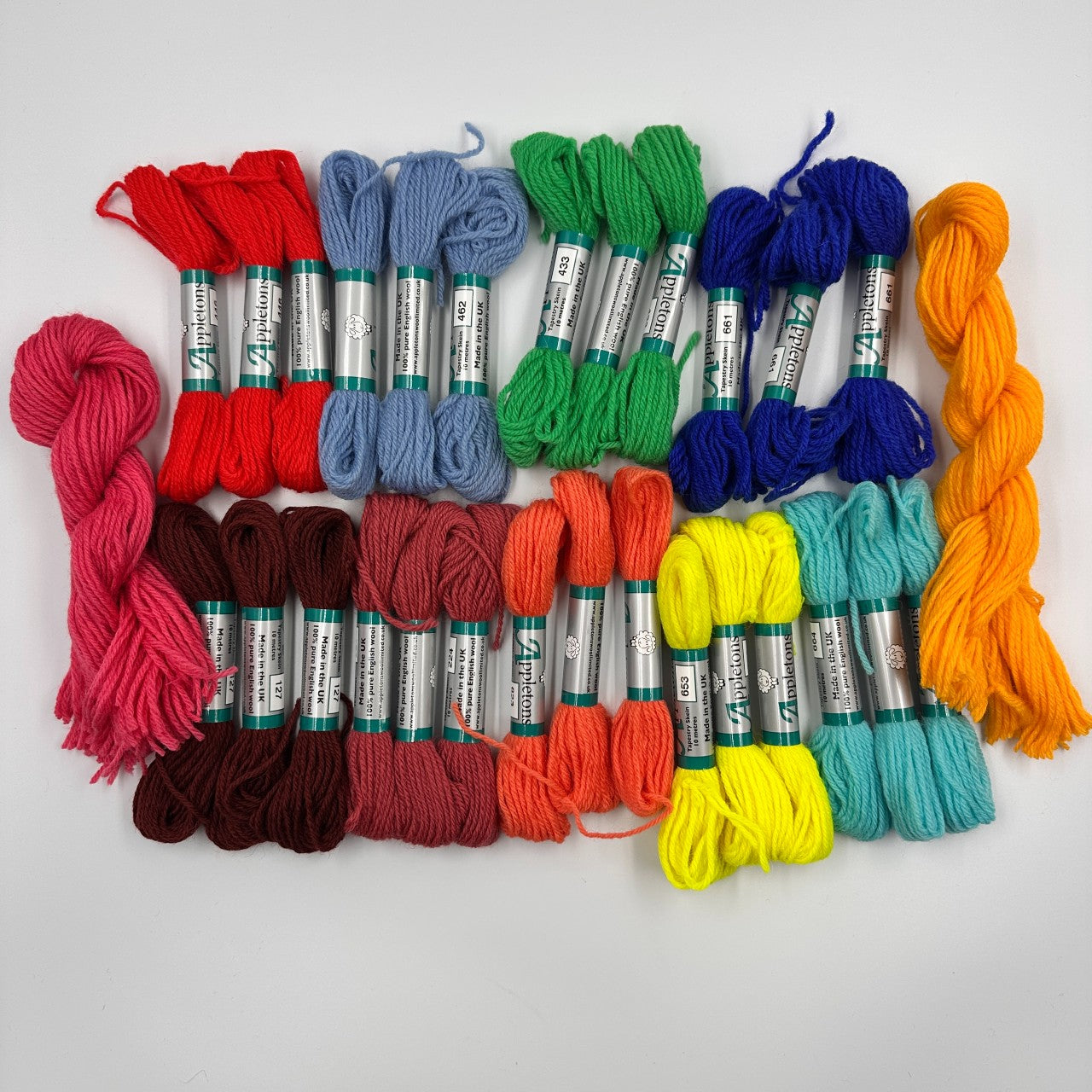 Assorted skeins of embroidery floss in various colors on a white background