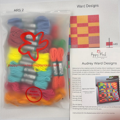 Poppy Monk needlepoint kit with colorful threads and a pattern guide on a white background