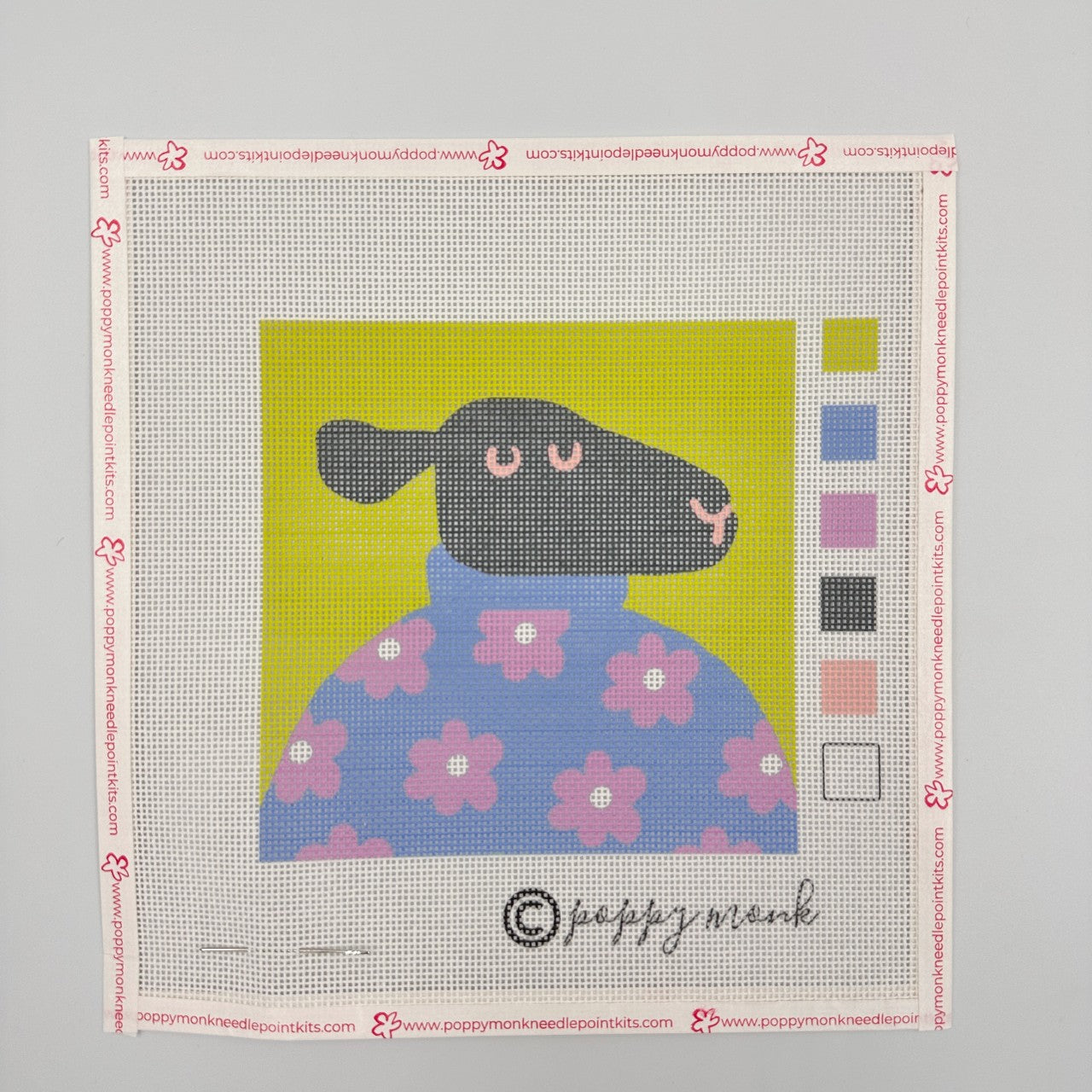 A needlepoint canvas of a black sheep wearing a sweater.