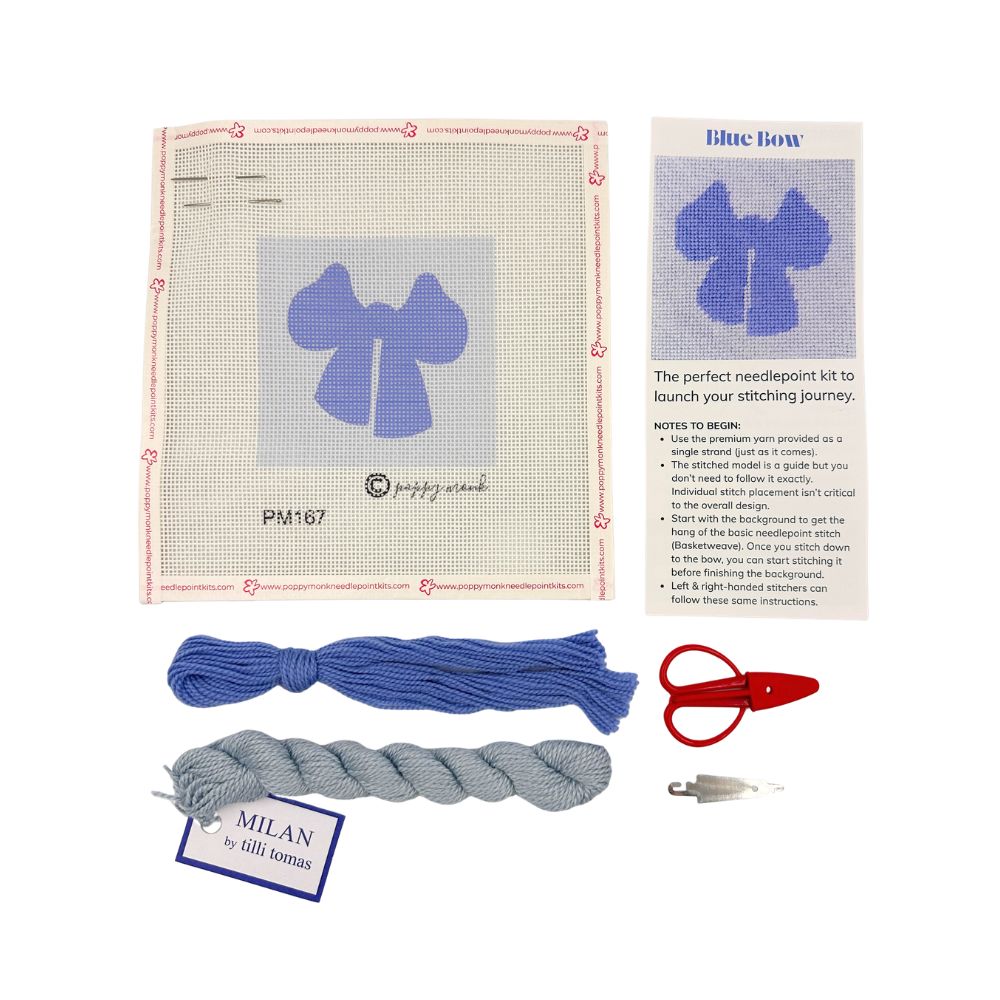 A needlepoint kit featuring a blue bow with threads and scissors