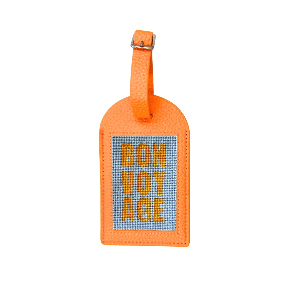 An orange textured leather luggage tag with a blue woven center panel featuring the words &