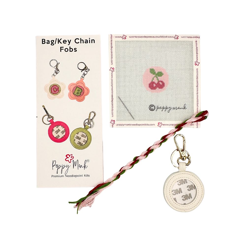 A needlepoint kit with a small round cherries design with fob hardware.