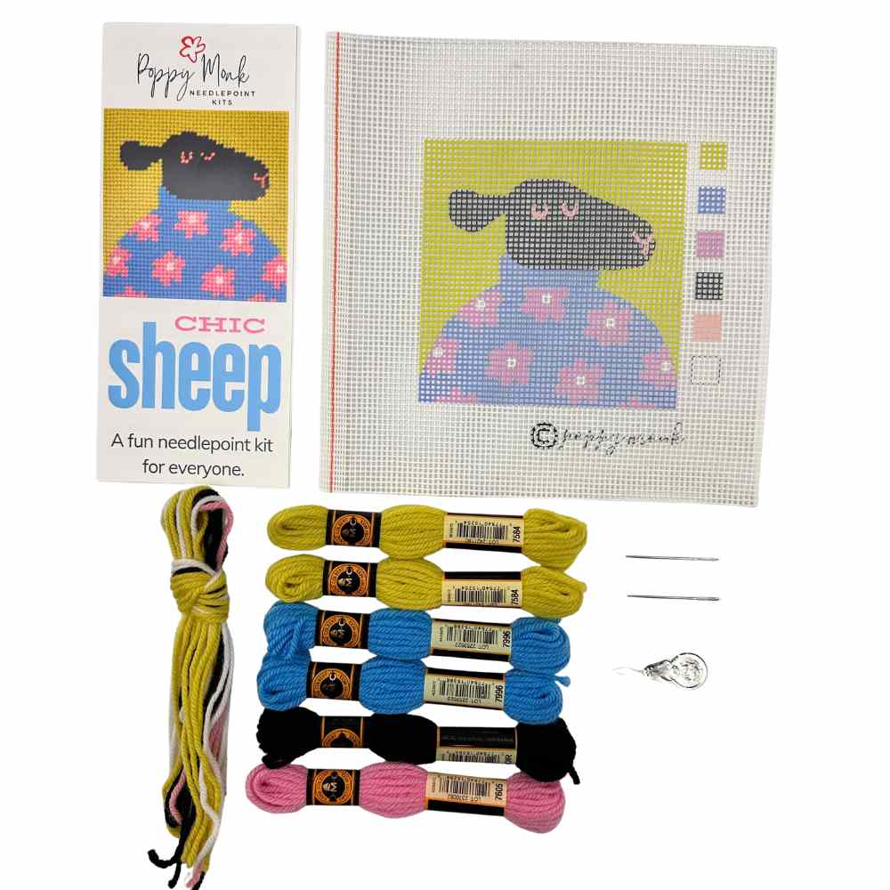 Needlepoint kit with a sheep design, threads, and needle on a white background