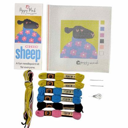 Needlepoint kit with a sheep design, threads, and needle on a white background