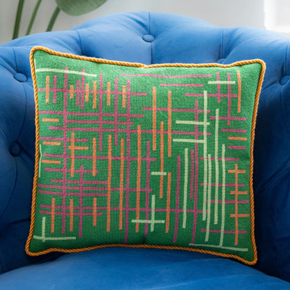 A needlepoint pillow with geometric lines on a green background