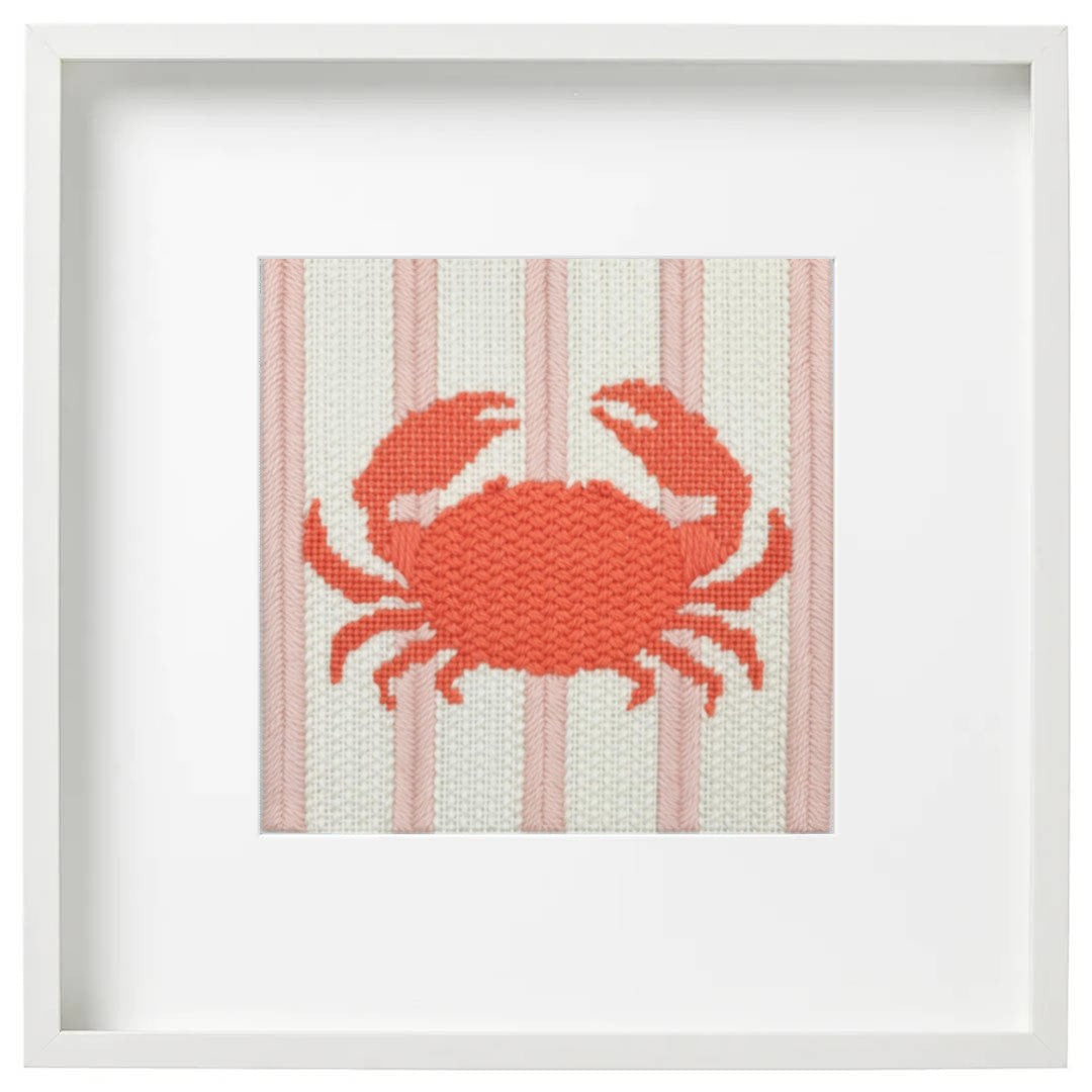 Framed needlepoint picture of a coral crab on a striped background