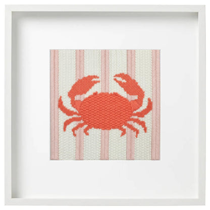 Framed needlepoint picture of a coral crab on a striped background