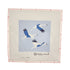 A square needlepoint canvas featuring three flying blue and white cranes on a light blue background, surrounded by a beige mesh border with a pink stitched edge and the brand name &