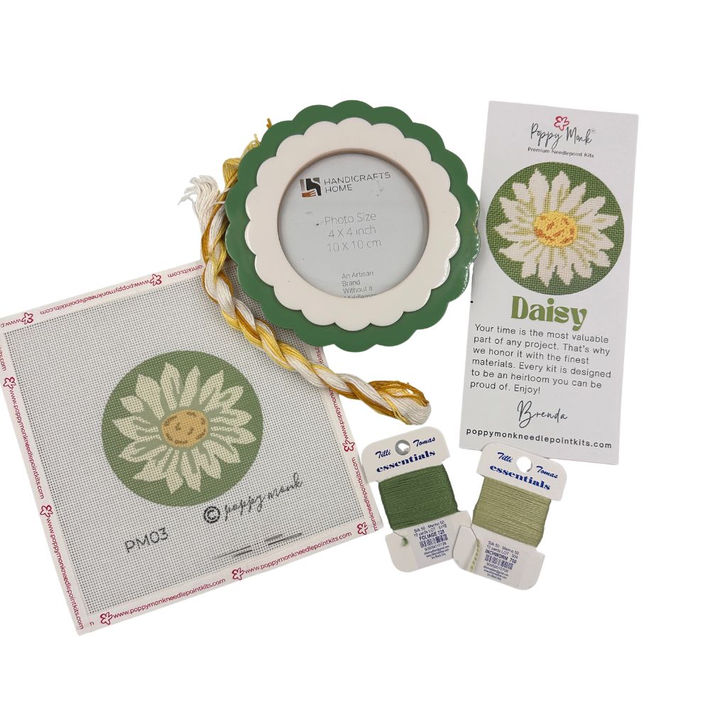 A needlepoint kit bundle with a daisy rund design and a scalloped frame