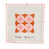 A geometric needlepoint design in orange and pinks shown in a white frame