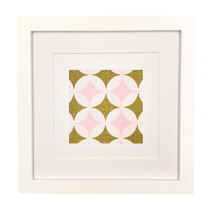 Geometric needlepoint design in olive green and pinks shown in a white frame
