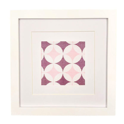 A geometric needlepoint design shown in a white frame