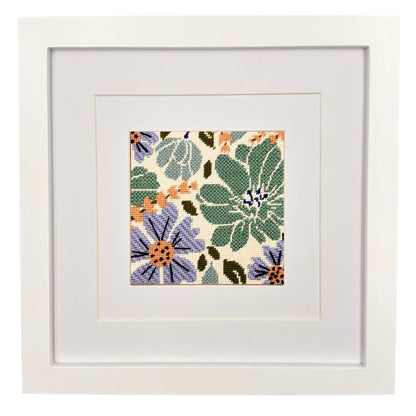 Framed needlepoint floral pattern on a white background