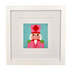 A framed needlepoint canvas featuring a nutcracker character on a teal background, presented in a white square frame with a white mat.