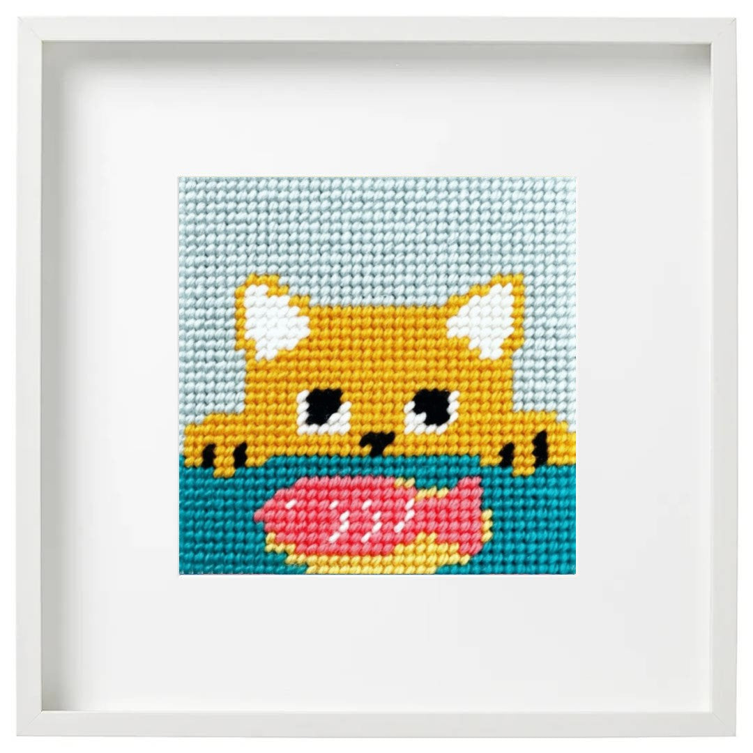 Needlepoint yellow cat eyeing a fish on a plate.