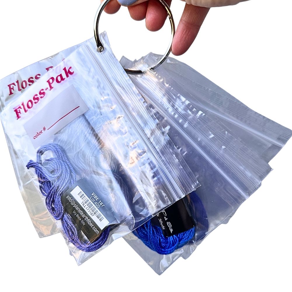 Clear plastic bag with blue thread and a keychain, labeled &